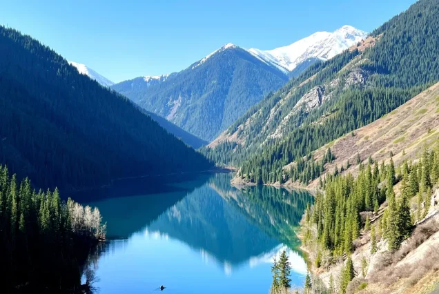 Tranquil waters of Kol Sai Lake surrounded by mountains.