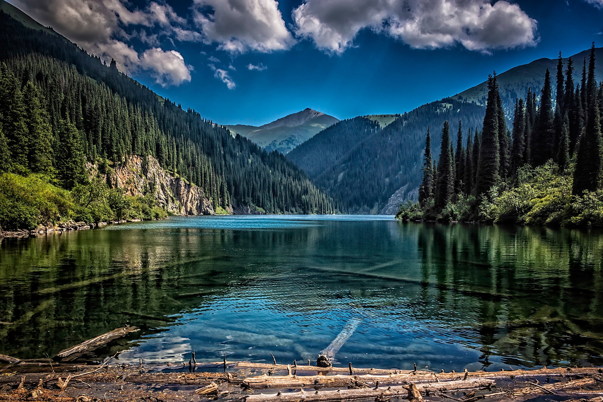 Tranquil waters of Kol Sai Lake surrounded by mountains.